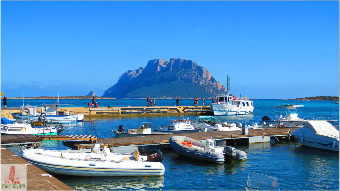 Porto San Paolo kikötője csónakokkal, háttérben Tavolarával